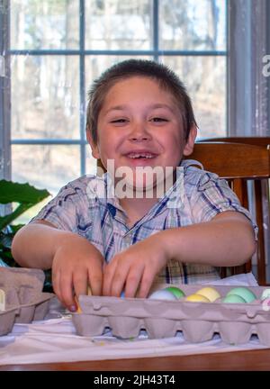 il ragazzo sorridente mostra con orgoglio le sue colorate uova di pasqua che ha appena tinto Foto Stock