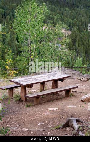 Un tavolo da picnic in legno si trova sulla cima di una montagna in una posizione panoramica nelle montagne rocciose del Colorado, negli Stati Uniti Foto Stock