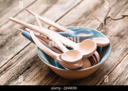 Cucchiai di argilla in ciotola su sfondo di legno Foto Stock