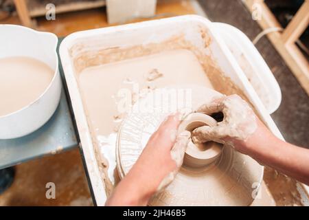 L'artista fa il fondo della ceramica sulla ruota della ceramica Foto Stock