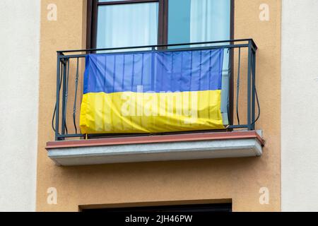 Bandiera dell'Ucraina su un balcone in una strada come sostegno dell'Ucraina Foto Stock