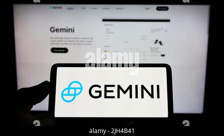 Persona che tiene il cellulare con il logo della società crittografica statunitense Gemini Trust Company LLC sullo schermo di fronte al sito web aziendale. Mettere a fuoco sul display del telefono. Foto Stock