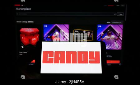 Persona che tiene uno smartphone con il logo della società americana NFT Candy Digital sullo schermo di fronte al sito web. Mettere a fuoco sul display del telefono. Foto Stock