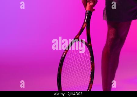 Immagine della sezione bassa del giocatore di tennis maschile afroamericano con illuminazione al neon viola e rosa Foto Stock