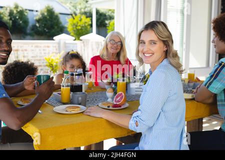 Ritratto di sorridente coppia multirazziale fare colazione con la famiglia al tavolo da pranzo a casa Foto Stock