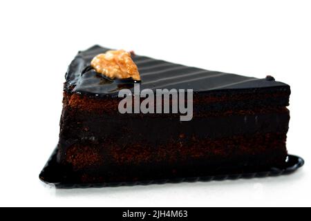 Torta di cioccolato fondente torta triangolare pezzo fatto di torta di fondente, noce, burro, vaniglia, farina, cioccolato e uova isolate su sfondo bianco, selezionare Foto Stock