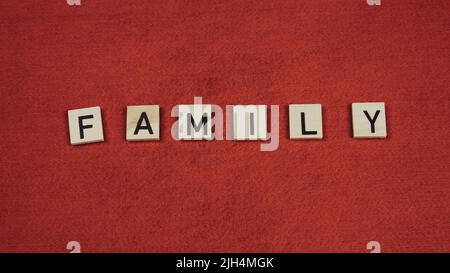 Parola 'Famiglia' composta da piastrelle di legno con lettere su sfondo rosso Foto Stock