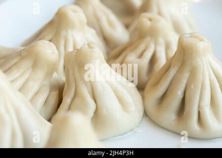 Cucina nazionale georgiana. Khinkali con carne. Khinkali su un tavolo bianco. Foto Stock