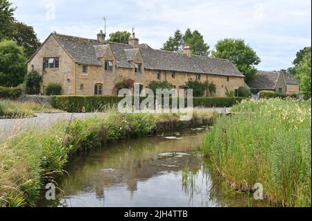 Il River Eye scorre attraverso il villaggio di Gloucestershire di macellazione inferiore con attraenti edifici in pietra Cotswold vecchio sullo sfondo Foto Stock