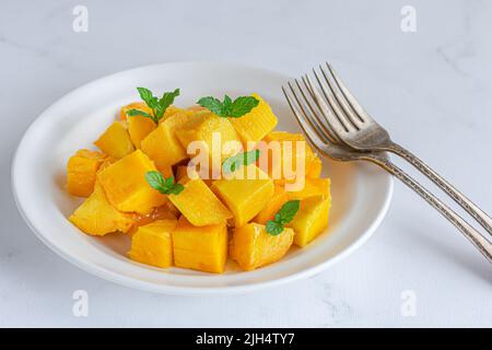 Cubi di mango freschi e maturi in un piatto su sfondo bianco Close-Up Photo Foto Stock