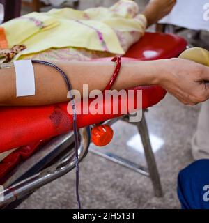 Donatore di sangue al campo di donazione di sangue tenuto con una palla rimbalzante in mano al Tempio Balaji, Vivek Vihar, Delhi, India, Image for World Blood Donor da Foto Stock