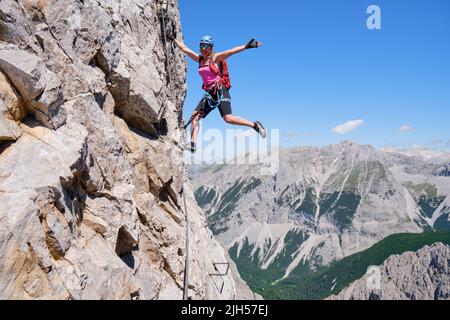 Una donna felice e attiva si aggancia in via ferrata Nordkette Innsbruck, Austria. Percorso roccioso a vista, avventura, attività, turismo, klettersteig. Foto Stock