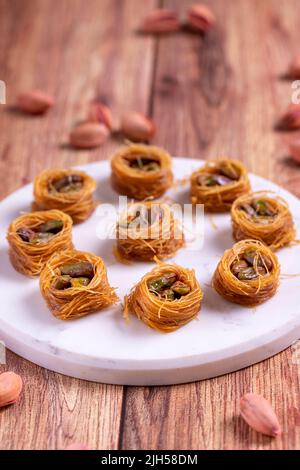 Bulbul Kadayif con Pistacchio. Kadayif baklava con riempimento di pistacchio su un pavimento di legno. Dessert di cucina turca. Primo piano. Nome locale Antep Fıstıklı Foto Stock