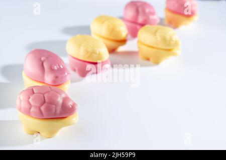 Vari animali commestibili ottenuti da marmellata da masticare con aggiunta di succhi naturali. Fiori gialli e rosa su sfondo bianco. sw. Bambini Foto Stock