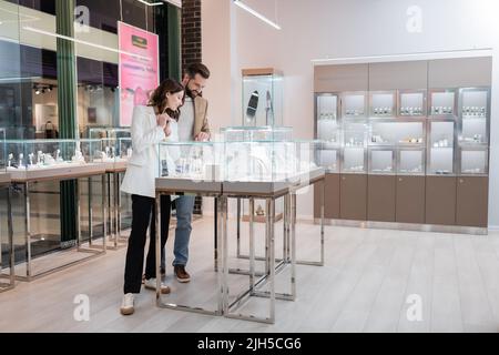 I clienti scelgono gli accessori vicino alla vetrina nel negozio di gioielli Foto Stock