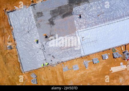 Durante la costruzione di un edificio, la plastica di barriera sarà installata prima che la fondazione di calcestruzzo sia versata Foto Stock