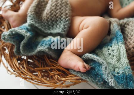 Gambe del bambino sdraiate sul supporto in vimini da vicino Foto Stock