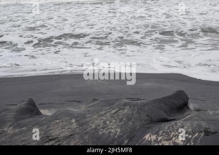 Prima vista di onde oceaniche schiumose che si infrangono lungo una spiaggia sabbiosa. Foto Stock