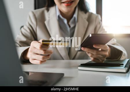 Primo piano le mani femminili in possesso di carta di credito e smartphone, giovane donna che paga online, utilizzando il servizio bancario, l'immissione di informazioni, shopping, ordini Foto Stock