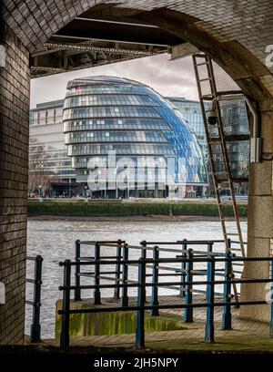 City Hall visto attraverso e incorniciato dai gradini lungo il fiume di Tower Bridge, Londra Foto Stock