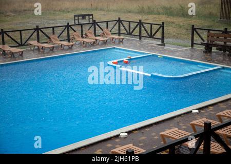 La pioggia incredibilmente pesante e il vento veloce e duro rovinano il caldo e soleggiato clima estivo nella base tranquilla con piscina per una vacanza attesa a lungo Foto Stock