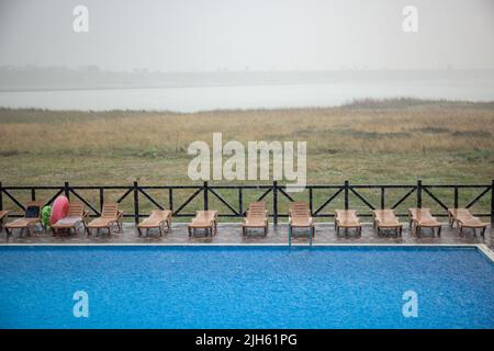 La pioggia incredibilmente pesante e il vento veloce e duro rovinano il caldo e soleggiato clima estivo nella base tranquilla con piscina per una vacanza attesa a lungo Foto Stock