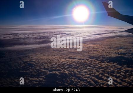 Airbus A220-300 ali in luci al tramonto che volano sopra le nuvole da qualche parte sopra la regione del Mar Baltico in Europa Foto Stock