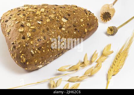 Pane nero con semi di sesamo e semi di girasole. Ramoscelli orzo e avena. Due papaveri Foto Stock