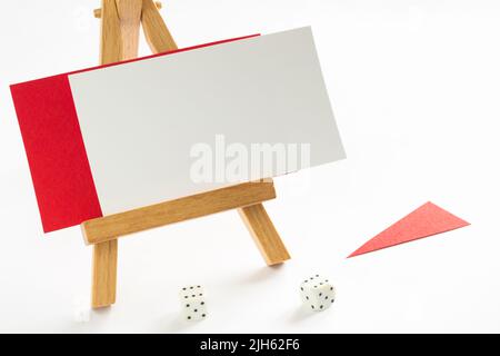 Cartoncino bianco e rosso adagiato su un piedistallo di legno. La freccia rossa su sfondo bianco. Dadi Foto Stock