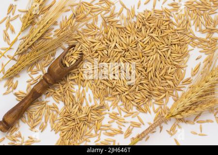 Sul tavolo sono sparsi avena, un cucchiaio di legno, grano e orzo Foto Stock