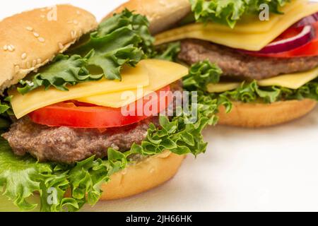 Burger Bun su foglia di lattuga con formaggio e pomodori. Primo piano. Sfondo bianco Foto Stock