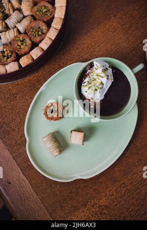 bere cioccolata calda in tazza verde e piatto abbinato con dolci baklava assortiti Foto Stock