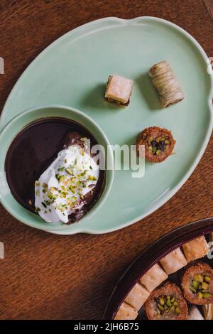 bere cioccolata calda in tazza verde e piatto abbinato con dolci baklava assortiti Foto Stock