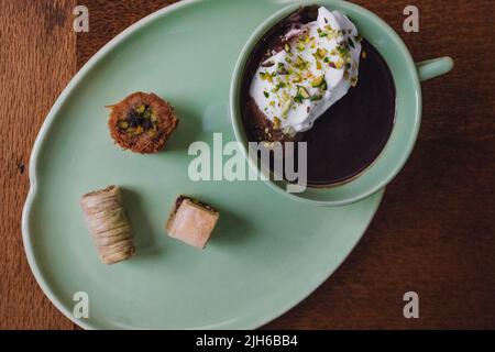 bere cioccolata calda in tazza verde e piatto abbinato con dolci baklava assortiti Foto Stock