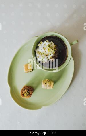 bere cioccolata calda in tazza verde e piatto abbinato con dolci baklava assortiti Foto Stock