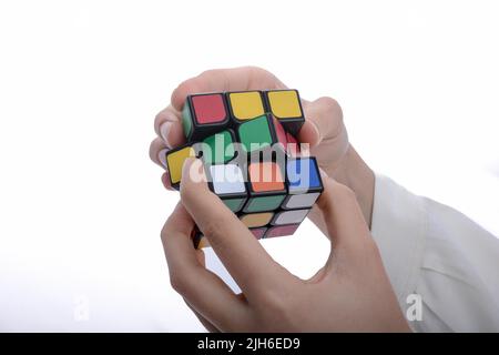 Bambino tenendo un cubo di Rubik in mano su uno sfondo bianco Foto Stock