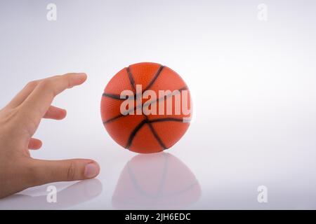 Mano che tiene un arancione modello di basket su sfondo bianco Foto Stock