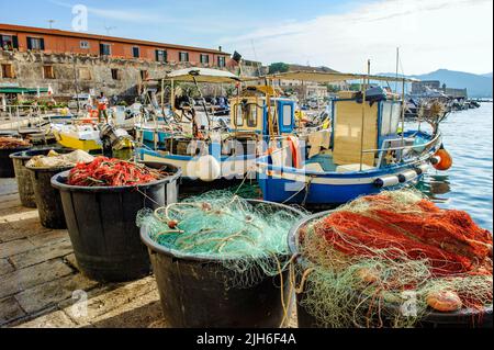 Vasche con reti da pesca rosse e verdi, dietro di esse piccole imbarcazioni da pesca locali ormeggiate al molo del vecchio porto di Portoferraio, Portoferraio, Elba Foto Stock