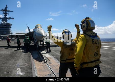 220714-N-VI910-2074 OCEANO PACIFICO (14 luglio 2022) Aviazione Boatswain’s Mate (Handling) 3rd Classe Luis Placencia, a destra, da Oakland, California, supervisiona Aviazione Boatswain’s Mate (Handling) Airman Najai Lopez-Patterson, da Albany, N.Y., mentre dirige un F/A-18E Super Hornet, assegnato al 151° Fighter, Sul ponte di volo della portaerei di classe Nimitz USS Abraham Lincoln (CVN 72) durante il Rim of the Pacific (RIMPAC) 2022. A partire da giugno partecipano a RIMPAC ventisei nazioni, 38 navi, quattro sottomarini, più di 170 aerei e 25.000 persone Foto Stock