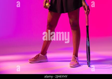 Immagine di una sezione bassa di tennista afro-americano con illuminazione al neon viola e rosa Foto Stock