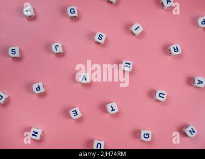 cubi o blocchi parola con lettere casualmente su uno sfondo rosa - il concetto di una ragazza neonato , scuola di educazione o di auto-educazione . Foto Stock