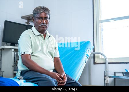 preoccupato pensieroso malato uomo anziano seduto a letto di ospedale - concetto di depressione, problemi di salute mentale e trattamento medico Foto Stock