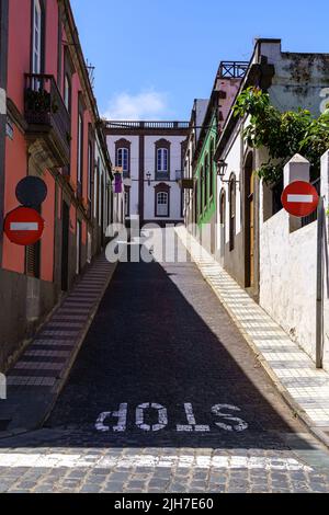 Strada molto ripida con un segnale di stop in fondo alla strada e case tipiche della città di Arucas in Gran Canaria. Foto Stock