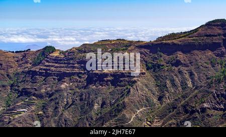 Vista sulle alte montagne dell'isola delle Canarie di Gran Canaria con le nuvole sottostanti all'orizzonte. Foto Stock