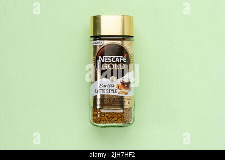 Tyumen, Russia-30 giugno 2022: Oro Nescafe stile barista latte. Caffè con aroma di caramello e pan di Spagna. Sfondo verde Foto Stock
