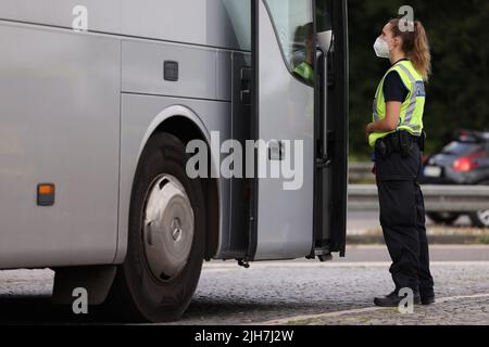 Ratingen, Germania. 16th luglio 2022. Un poliziotto controlla un pullman presso l'area di servizio Hösel sulla superstrada A3 vicino Ratingen. La polizia utilizza il punto intermedio delle vacanze estive come opportunità per controlli sul traffico a livello nazionale. Credit: David Young/dpa/Alamy Live News Foto Stock