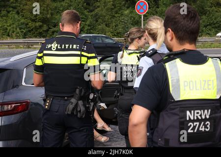 Ratingen, Germania. 16th luglio 2022. Un poliziotto olandese e un poliziotto tedesco controllano un veicolo presso l'area di servizio di Hösel sulla superstrada A3 vicino Ratingen. La polizia sta utilizzando il punto intermedio della vacanza estiva come opportunità per controlli sul traffico a livello nazionale. Credit: David Young/dpa/Alamy Live News Foto Stock