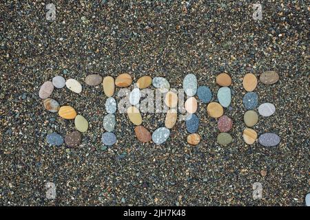 Testo pietra fatta di pietre su spiaggia sabbiosa. Foto Stock