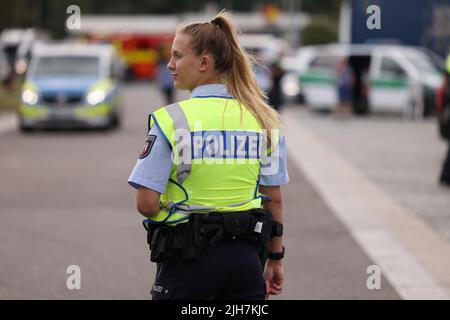 Ratingen, Germania. 16th luglio 2022. Un poliziotto controlla il traffico nell'area di servizio di Hösel sull'autobahn A3. La polizia utilizza il punto intermedio delle vacanze estive come opportunità per controlli sul traffico a livello nazionale. Credit: David Young/dpa/Alamy Live News Foto Stock