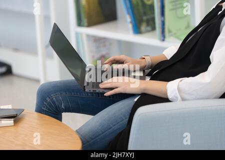Non identificato donna uso notebook per il lavoro in pubblico o biblioteca - concetto di lavoro Foto Stock